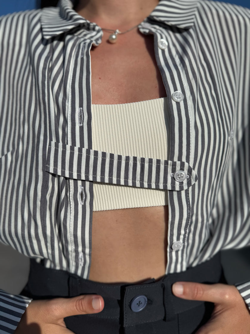 Person wearing a striped shirt over a ribbed top with a blurred background
