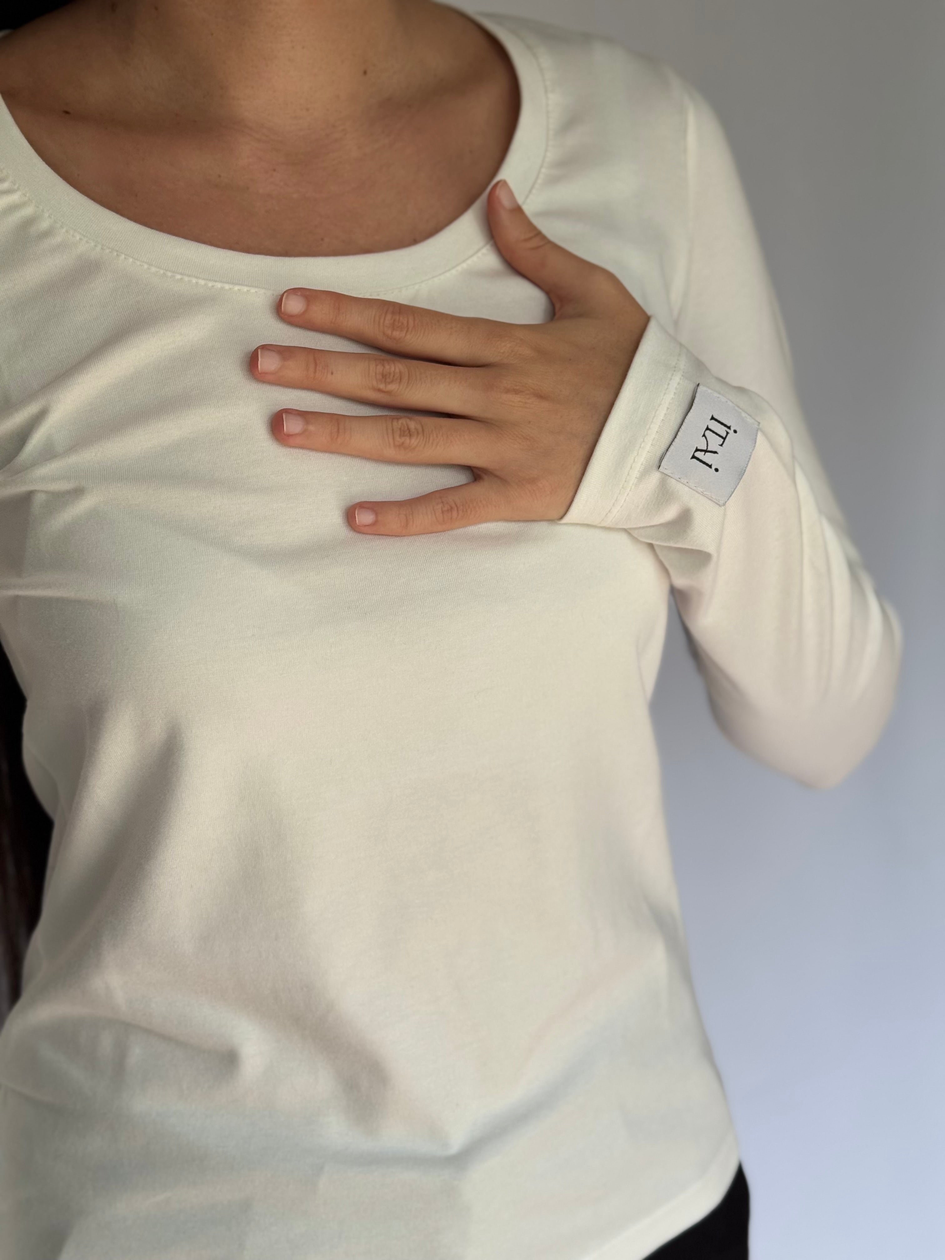 A young woman wearing a white long-sleeve shirt with a visible ITAI brand label on a sleeve