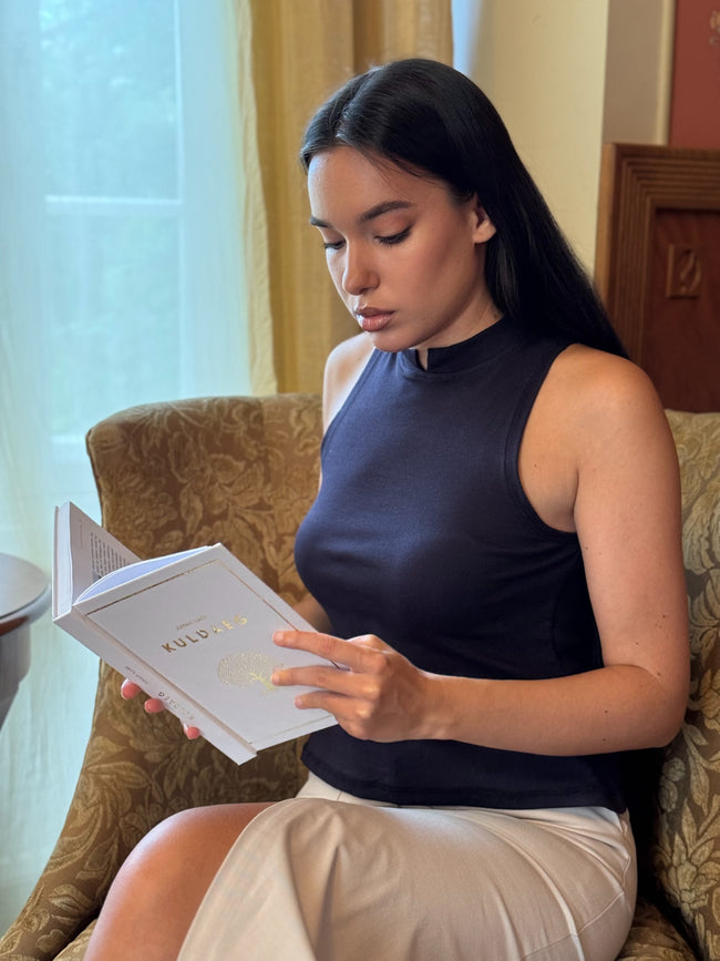 Woman reading a book in a cozy room with curtains and furniture.
