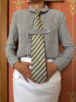 Person wearing a striped shirt with a long tie against a decorative wall.
